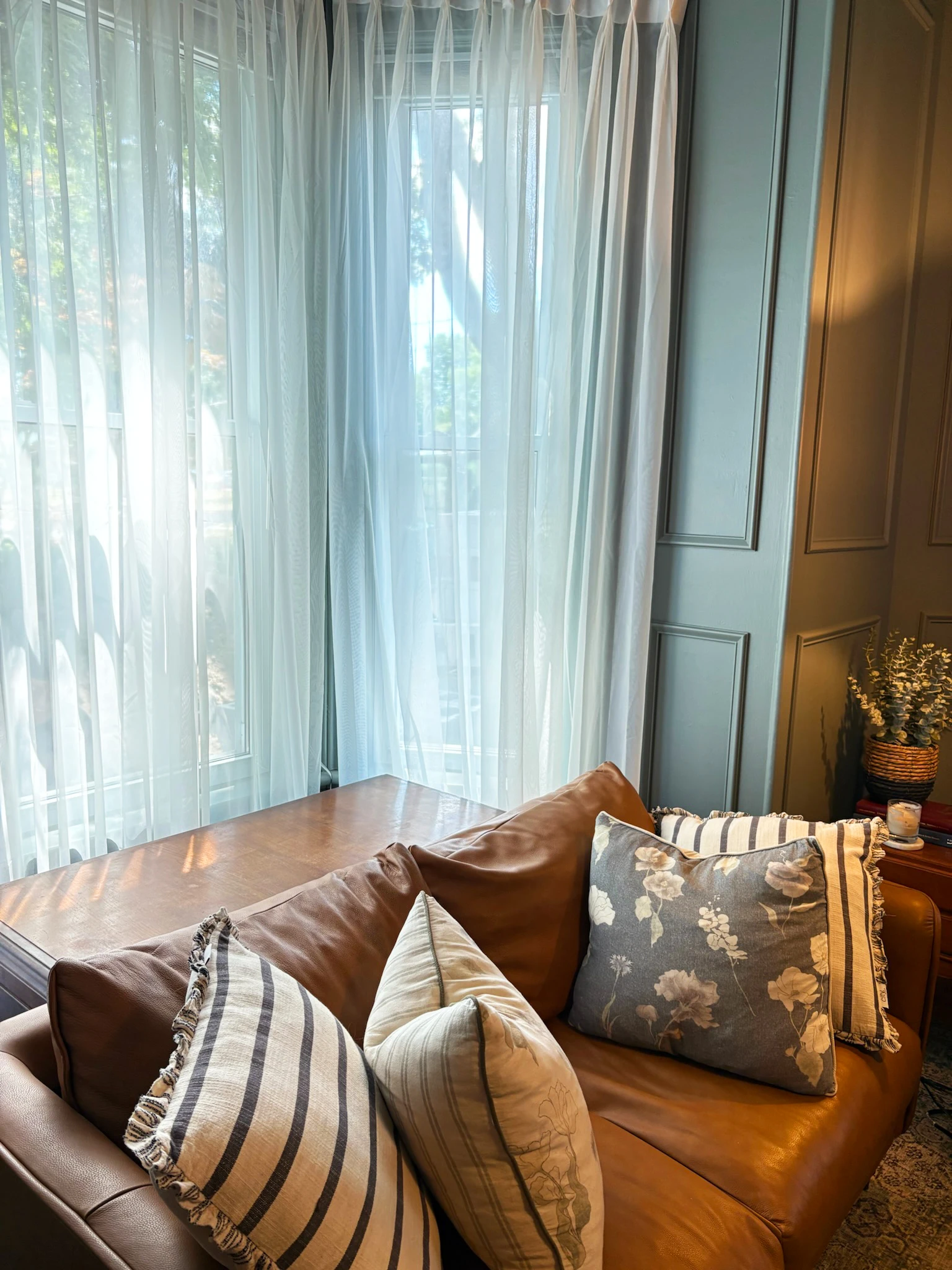 Leather sofa with pillows and sheer curtains in the living room