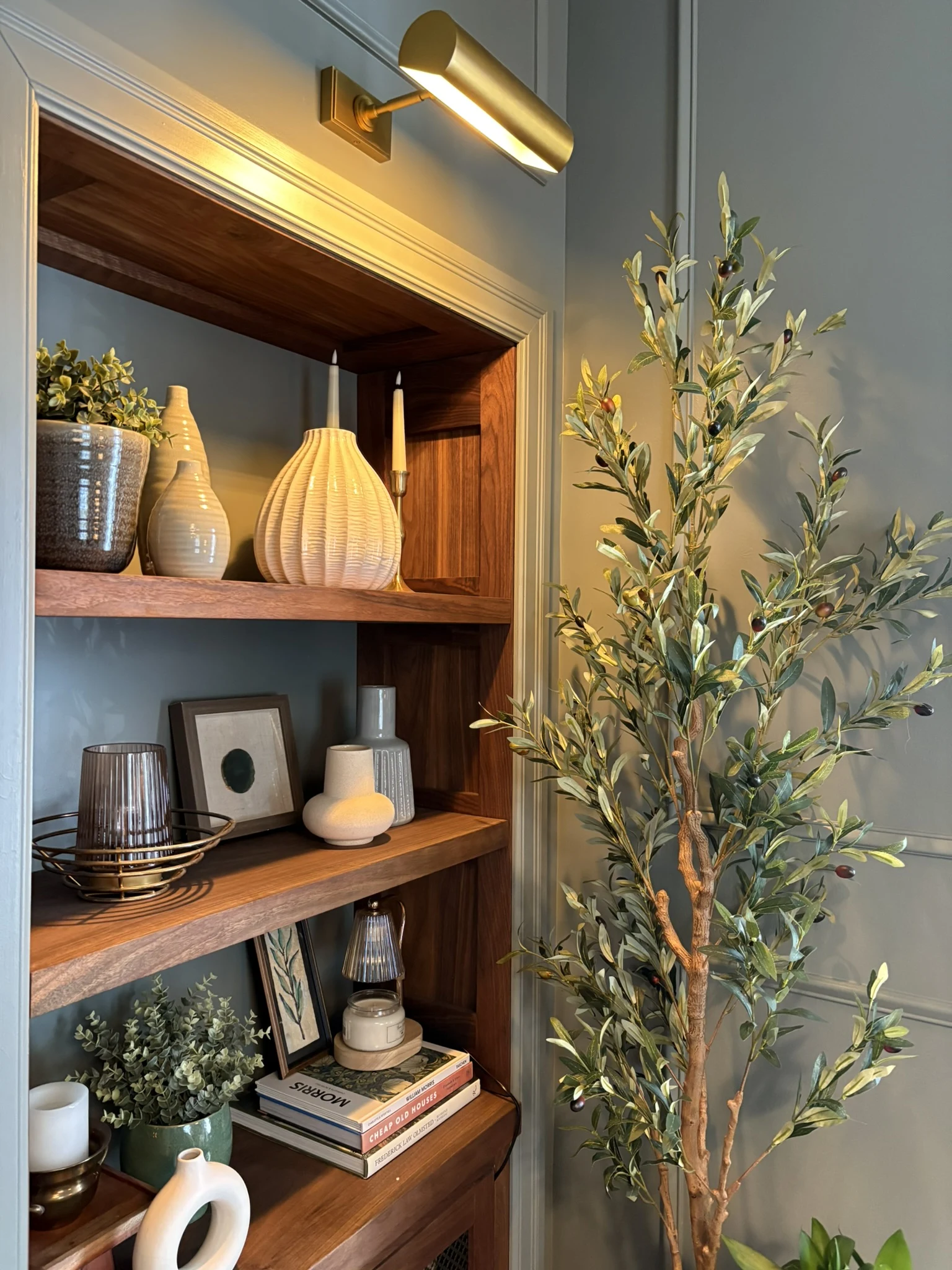 Styled living room built-in shelving with picture light and greenery