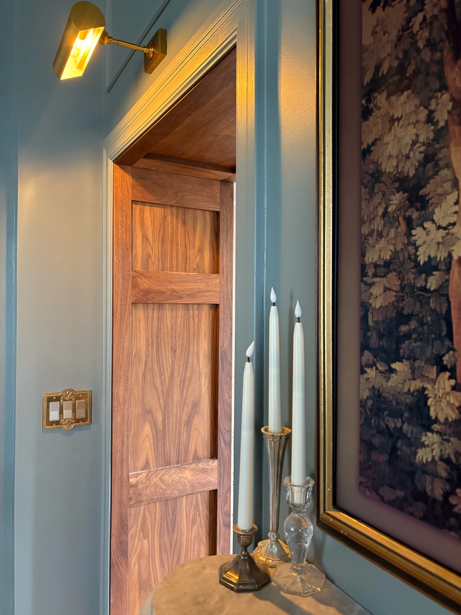 Paneled living room wall with wood doorway, picture light, and candles