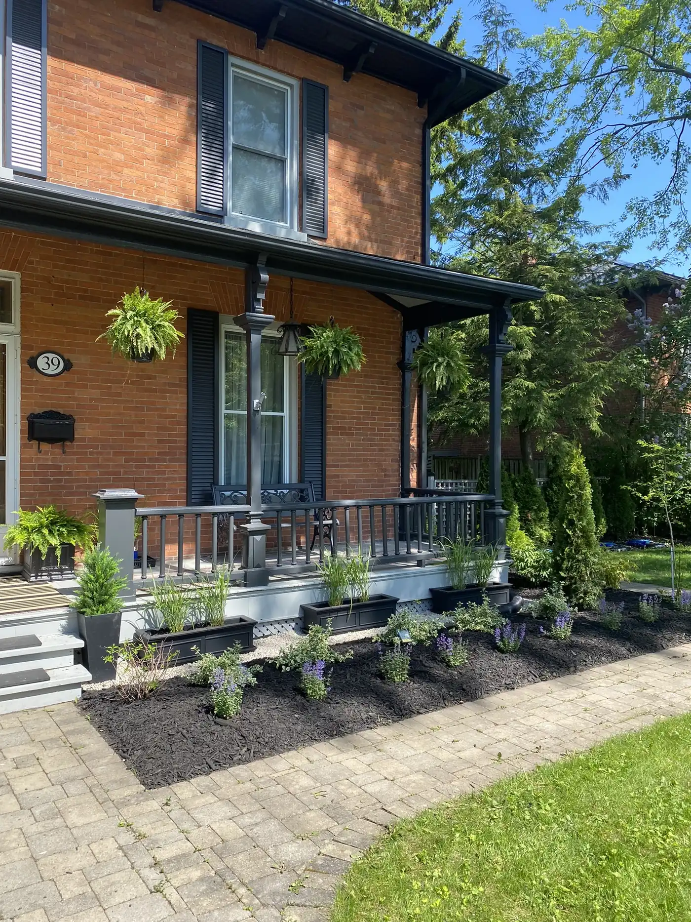 Historic brick home porch with layered front garden planting and walkway