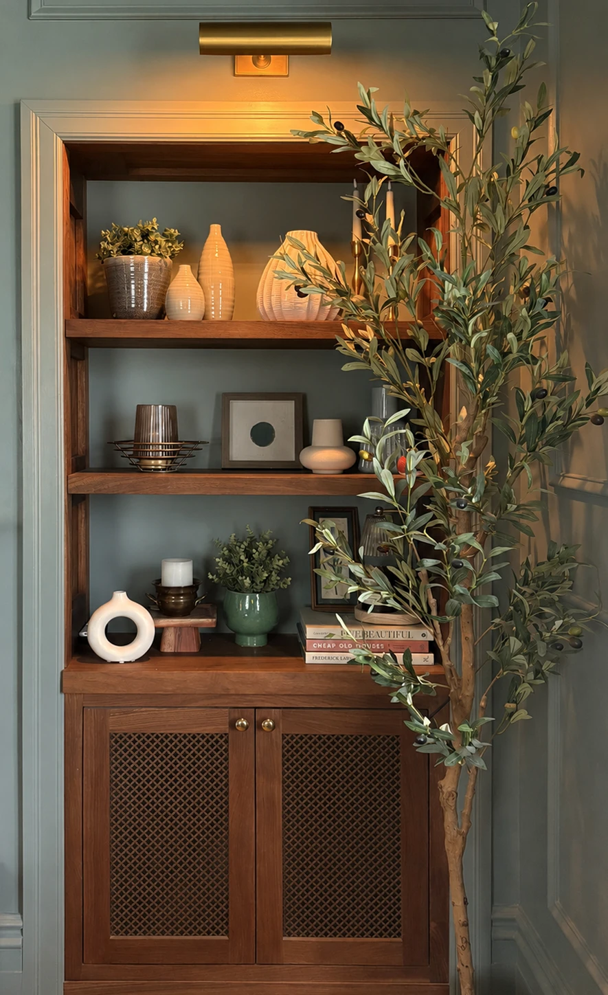 Custom built-in millwork with warm wood shelving, panelled walls, and brass picture light