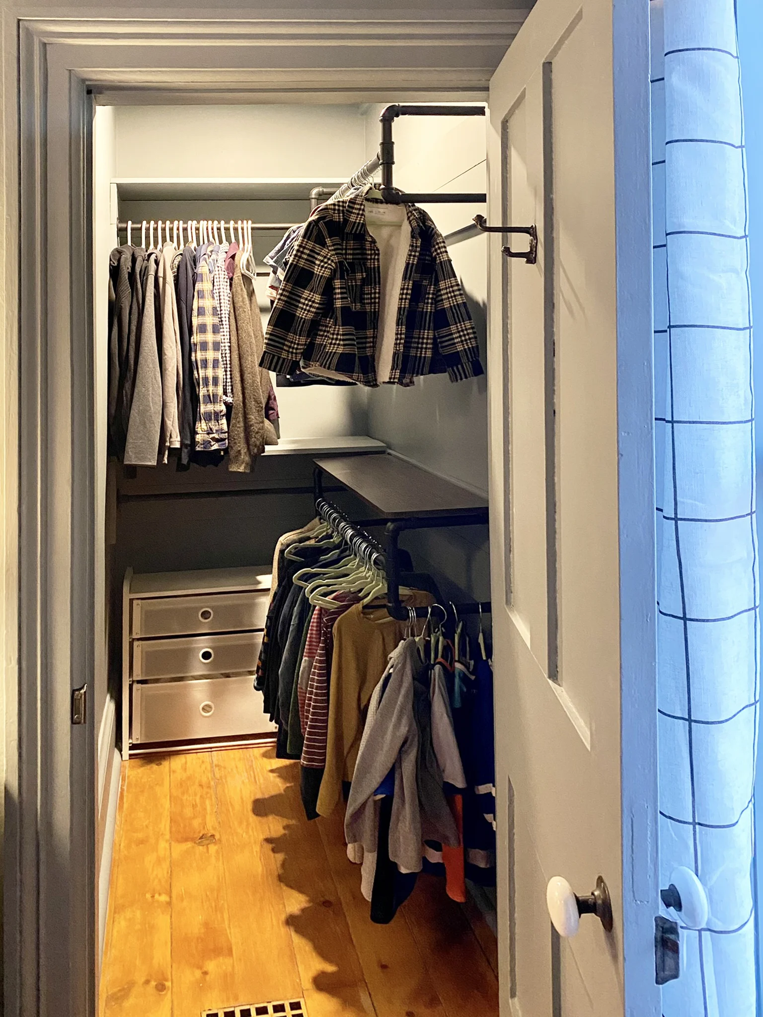 Bedroom closet with hanging storage, folded clothing, and wood floor detail