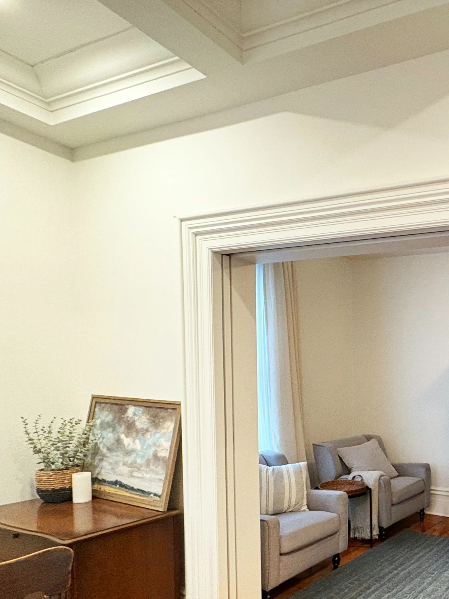 Dining room corner looking through to adjacent sitting room with coffered ceiling and layered seating
