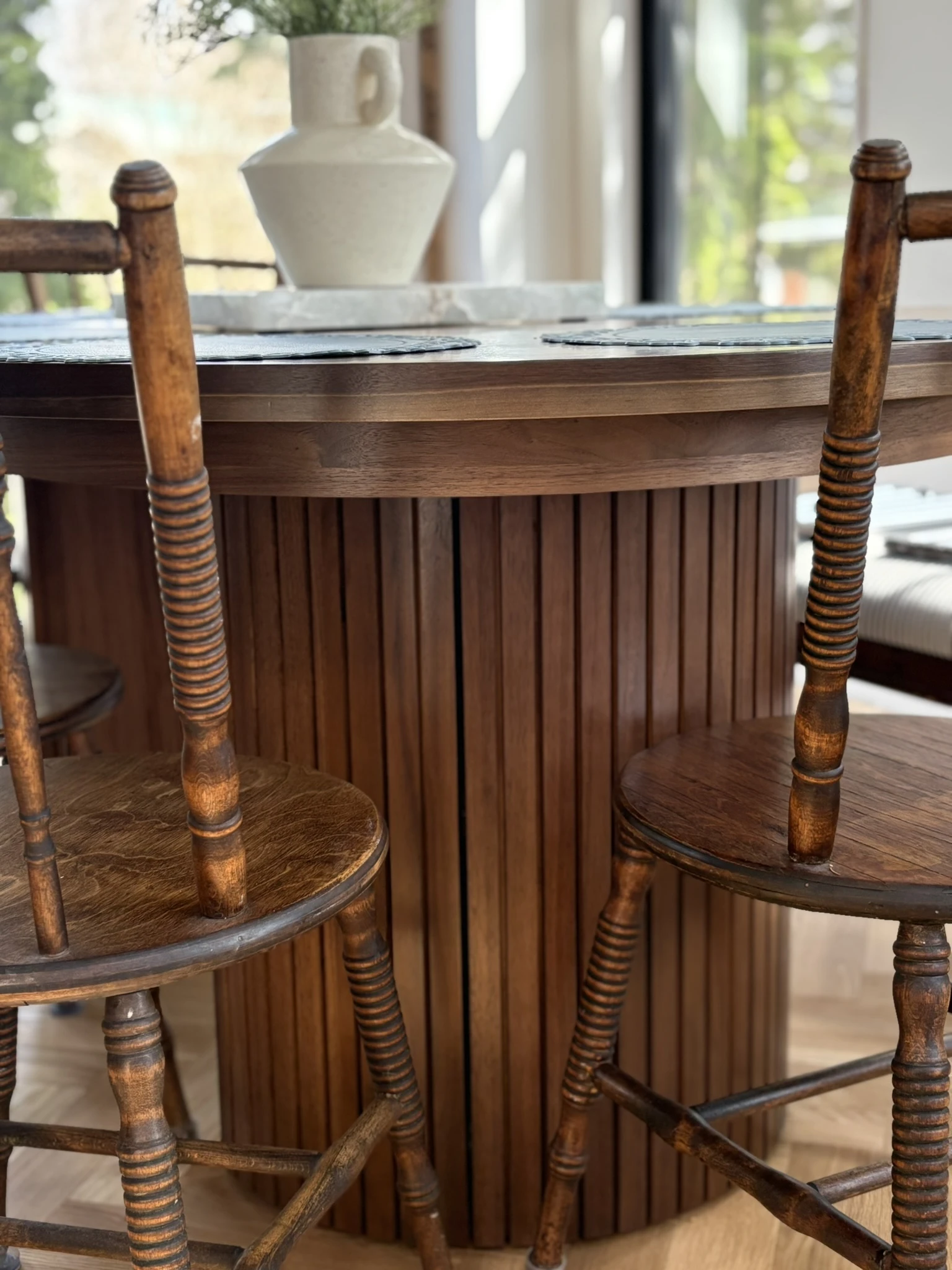 Wood island detail with antique stools and a marble-topped dining area