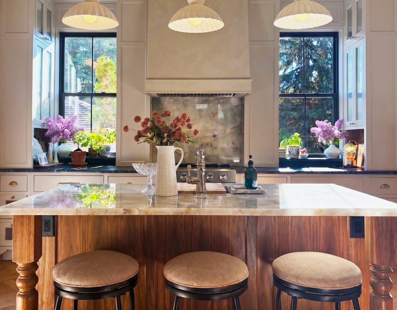 Layered residential kitchen with custom cabinetry, marble island, and pendant lighting