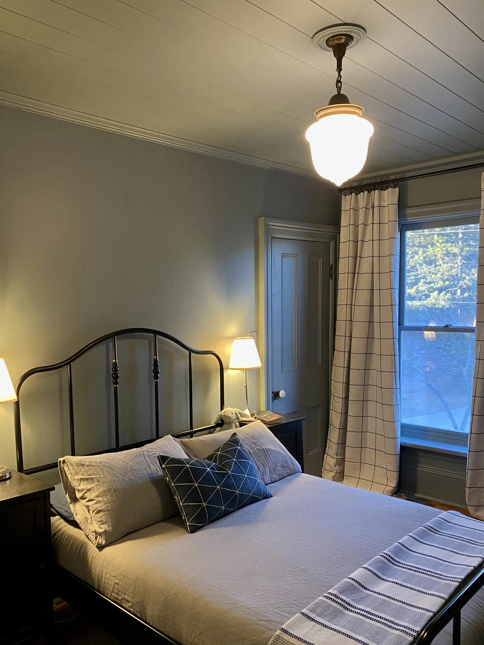 Layered bedroom with warm lighting, paneled walls, and classic textiles